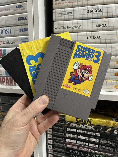 Cartucho de Super Mario Bros. 3 para NES diante do manual com a capa do jogo